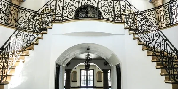 Elegant dual staircase with ornate iron railings in a bright interior